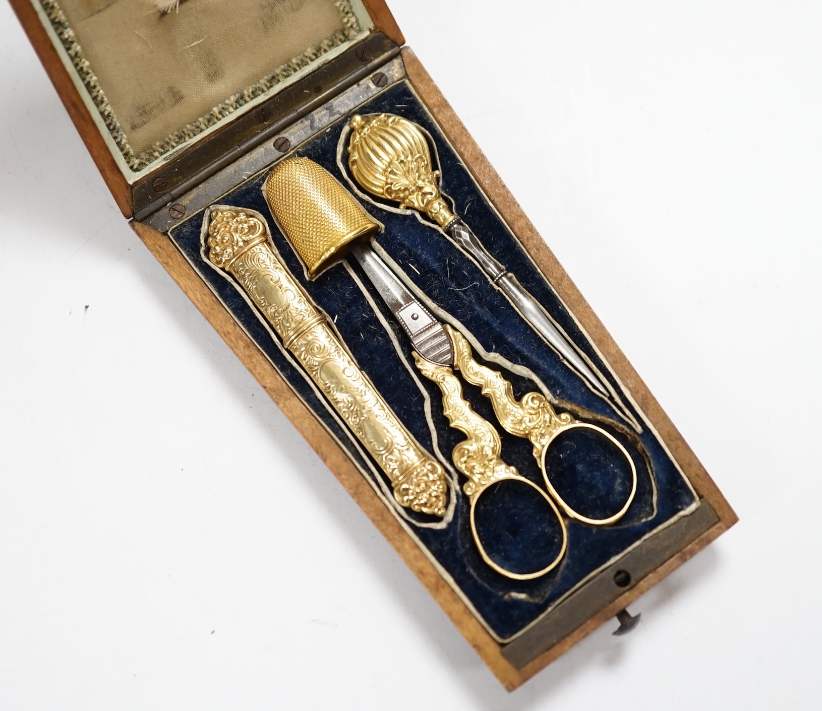 A French four piece yellow metal (18ct poincon mark) necessaire, comprising a thimble, pair of mounted scissors, hole maker and needle case, in fitted rosewood case.